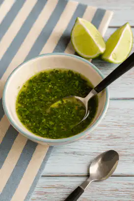 Molho de limão com coentro picado em tigela branca com borda azul clara
