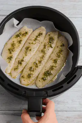 Filés de peixe crus cobertos com molho verde na air fryer